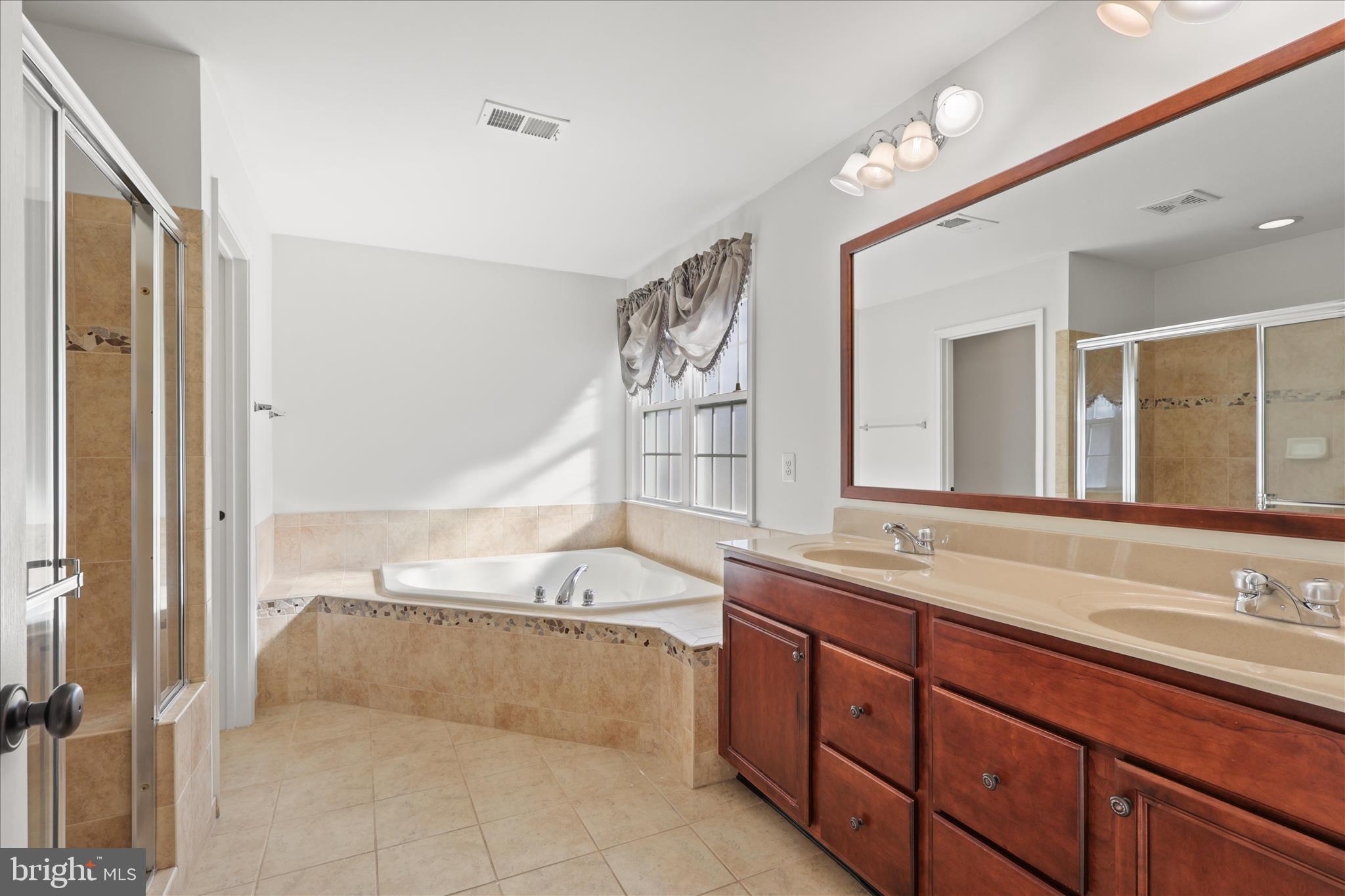 15221 Londons Bridge Road Haymarket, VA 20169 - Photo 13 of 43 a spacious bathroom with a tub sink and mirror