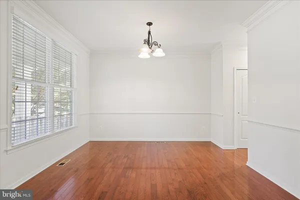 an empty room with wooden floor cabinet and windows