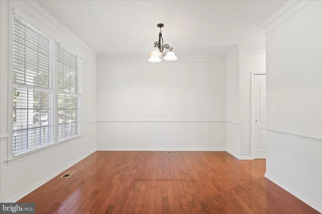 an empty room with wooden floor cabinet and windows