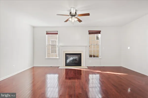 a view of a room with wooden floor a fireplace a ceiling fan and wooden floor