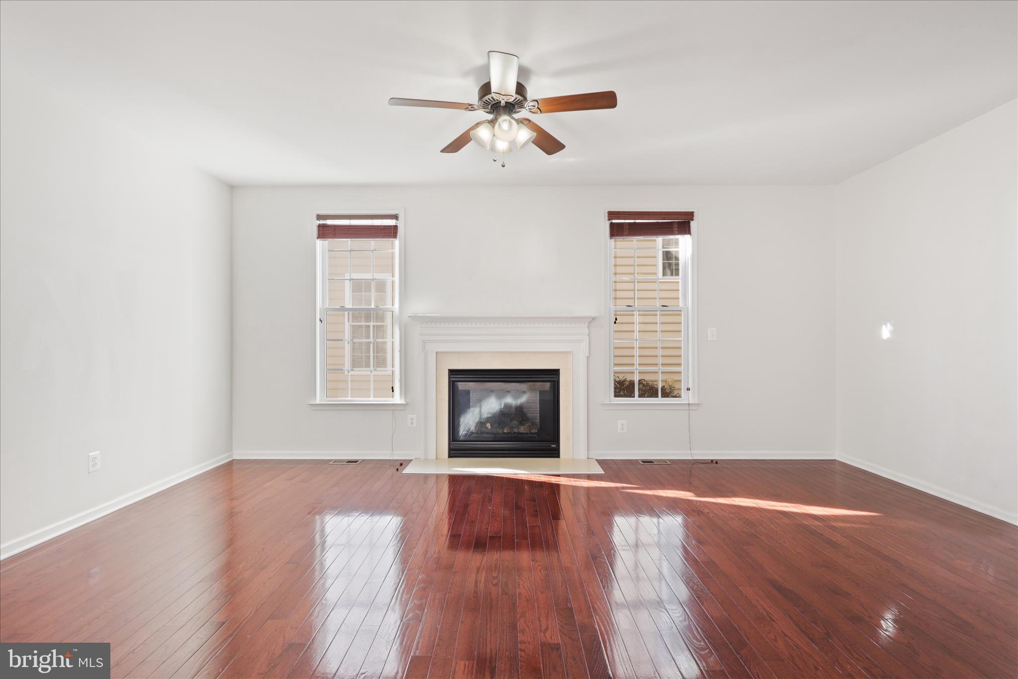 15221 Londons Bridge Road Haymarket, VA 20169 - Photo 9 of 43 a view of a room with wooden floor a fireplace a ceiling fan and wooden floor