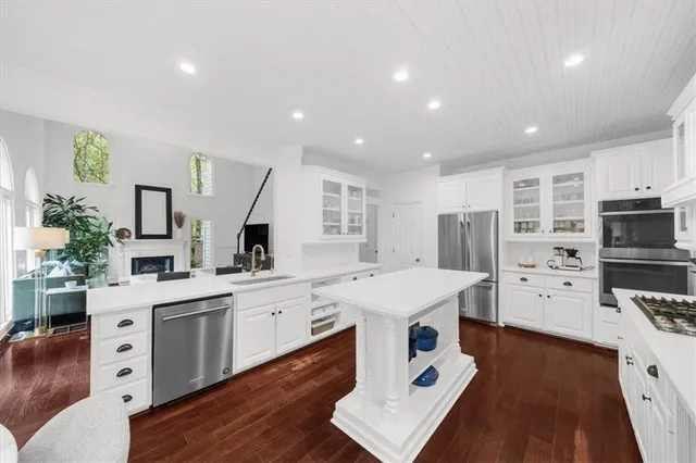 a kitchen with stainless steel appliances kitchen island granite countertop a stove a sink a refrigerator and a dining table with wooden floor