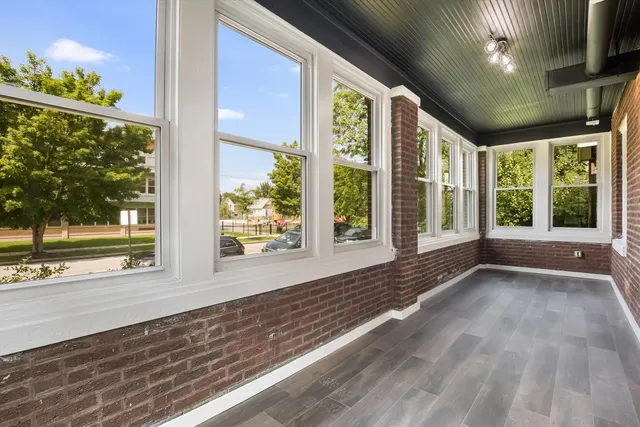 a view of an empty room with a window and hardwood floor