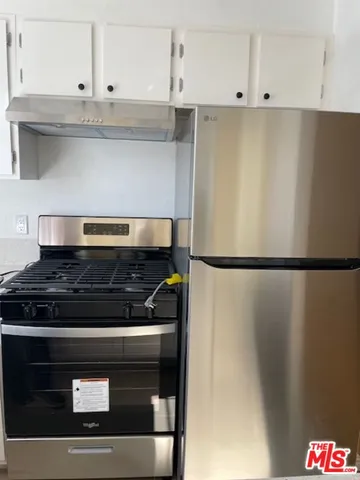 a kitchen with granite countertop white cabinets and refrigerator