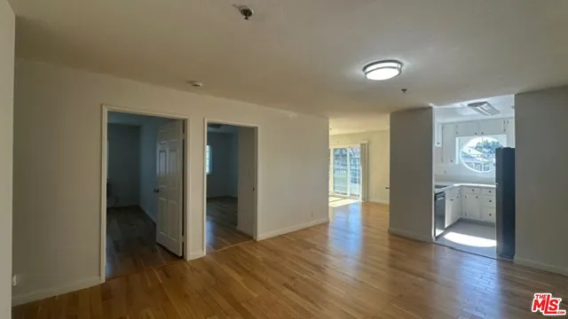 a view of an empty room with wooden floor and a window