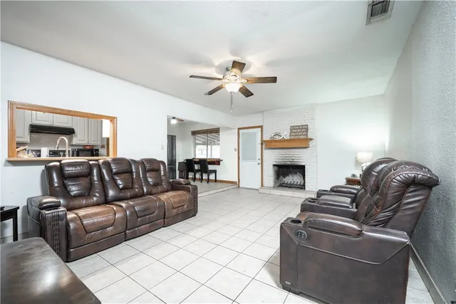 a living room with furniture a fireplace and a ceiling fan