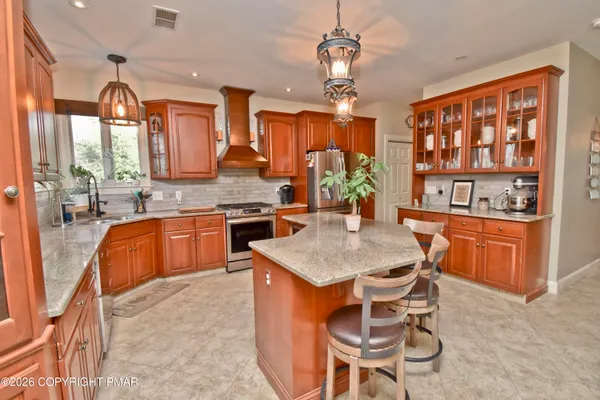 a open kitchen with stainless steel appliances granite countertop a stove a refrigerator a sink a dining table and chairs with wooden floor