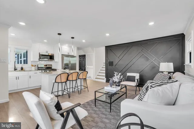 a living room with stainless steel appliances kitchen island granite countertop furniture and a ceiling fan