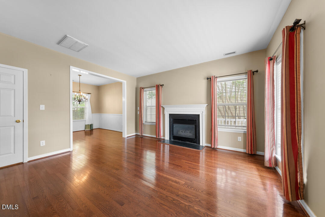 5324 Bartram Place Raleigh, NC 27617 - Photo 4 of 35 an empty room with wooden floor fireplace and windows