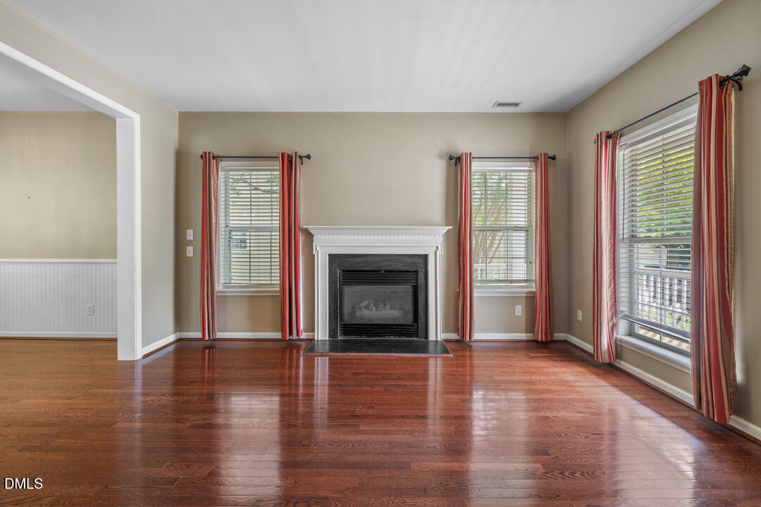 5324 Bartram Place Raleigh, NC 27617 - Photo 7 of 35 an empty room with wooden floor fireplace and windows