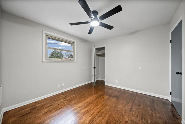 an empty room with wooden floor and ceiling fan
