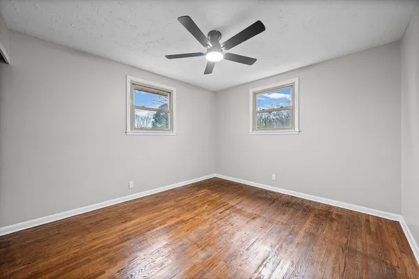 an empty room with wooden floor and ceiling fan