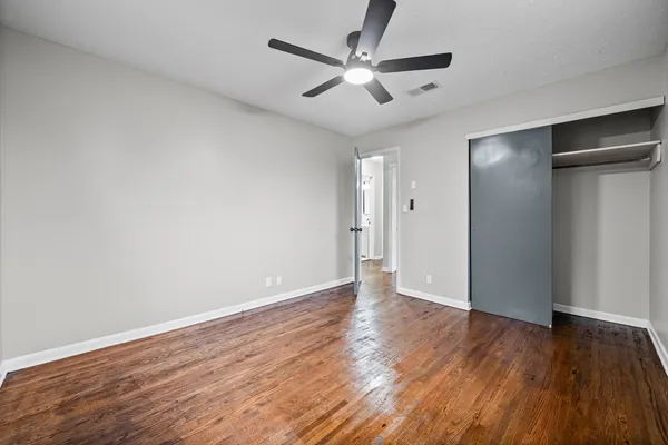 an empty room with wooden floor and a ceiling fan