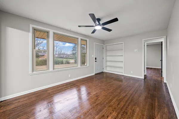 a view of empty room with wooden floor and fan
