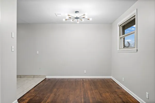 an empty room with wooden floor and chandelier