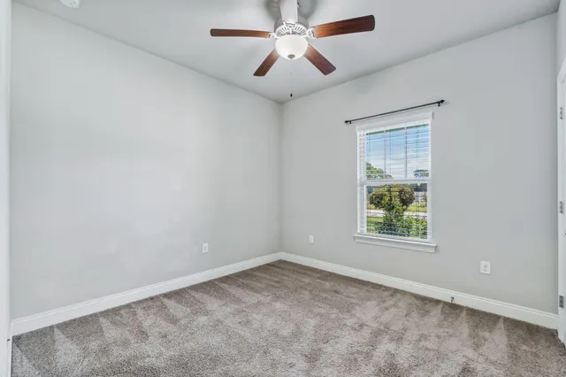 an empty room with windows and ceiling fan