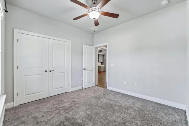 an empty room with closet and a ceiling fan