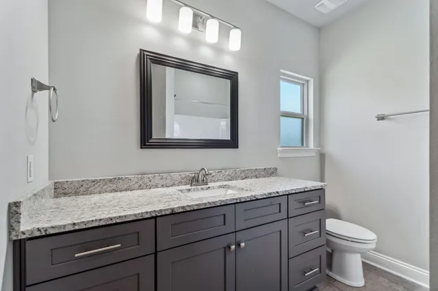 a bathroom with a granite countertop toilet sink and mirror