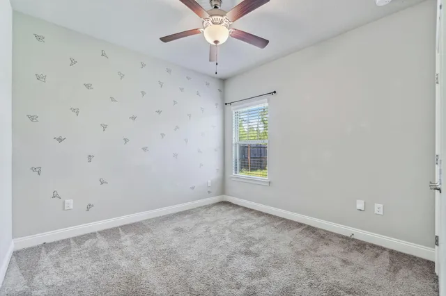an empty room with a window and a fan