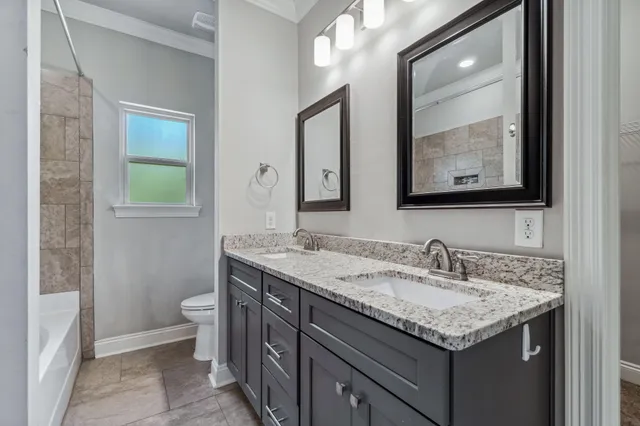a bathroom with a granite countertop sink toilet and mirror