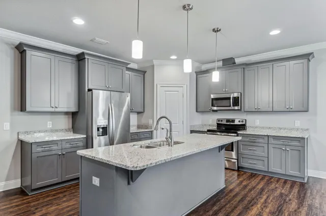 a kitchen with stainless steel appliances granite countertop a sink a stove a refrigerator cabinets and a kitchen island