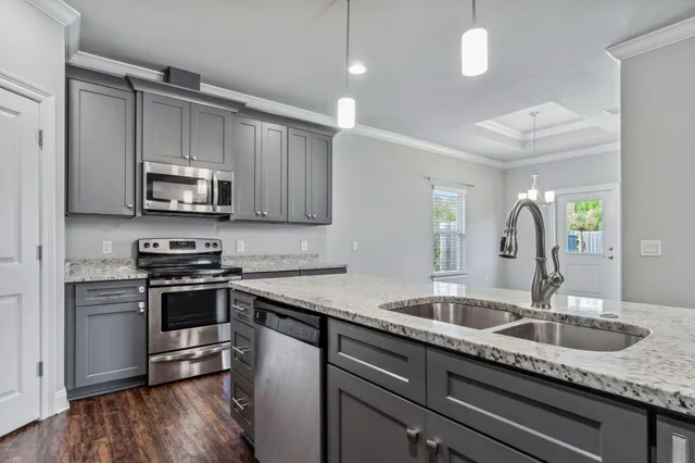 a kitchen with granite countertop a sink stainless steel appliances and cabinets