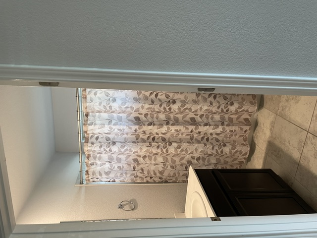 12401 Amber Lynn Path Manor, TX 78653 - Photo 22 of 33 The compact bathroom features a patterned shower curtain and essential vanity storage.
