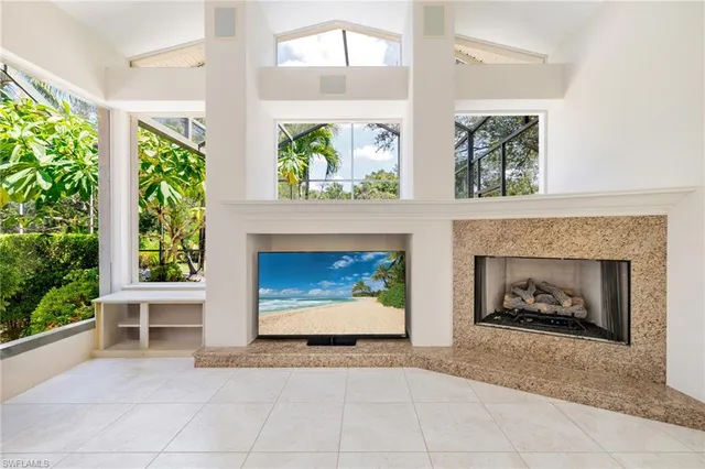 a living room with a fireplace windows and a potted plant
