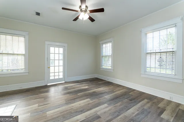 a view of an empty room with wooden floor and a window