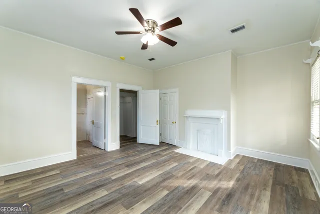 an empty room with wooden floor and a ceiling fan