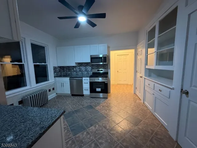 a kitchen with stainless steel appliances granite countertop a stove top oven a sink and a refrigerator