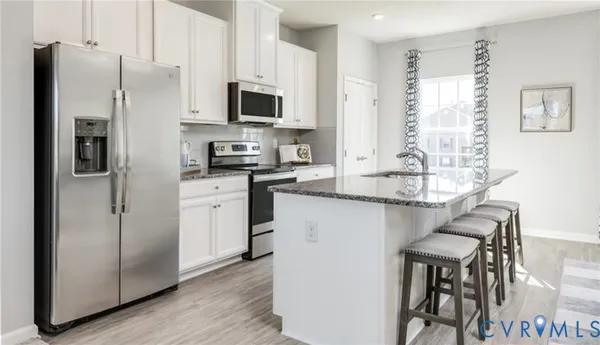 a kitchen with stainless steel appliances granite countertop a refrigerator a stove a sink a dining table and chairs