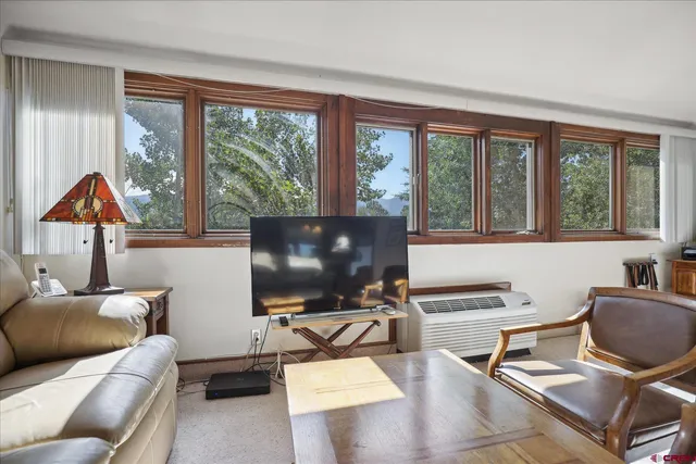 a living room with furniture a flat screen tv and a floor to ceiling window