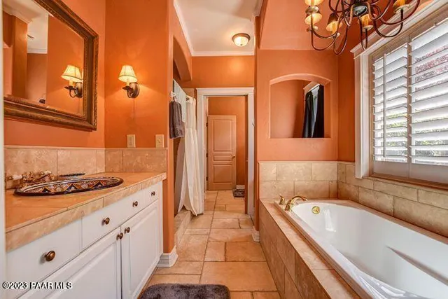 a bathroom with a granite countertop tub a sink and a large mirror next to a window