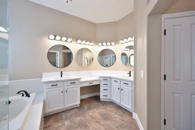 a bathroom with a double vanity sink mirror and bathtub