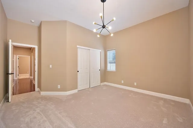 a view of an empty room with a chandelier fan