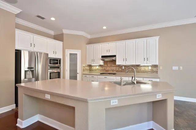 a kitchen with stainless steel appliances a sink a stove a microwave a refrigerator and cabinets