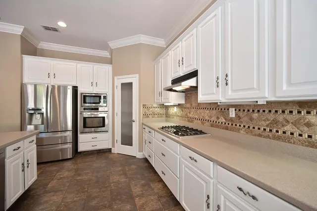 a kitchen with granite countertop a refrigerator sink and cabinets