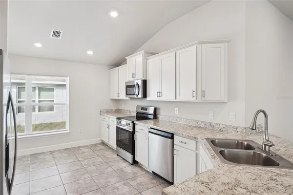 a kitchen with granite countertop a sink stainless steel appliances and white cabinets