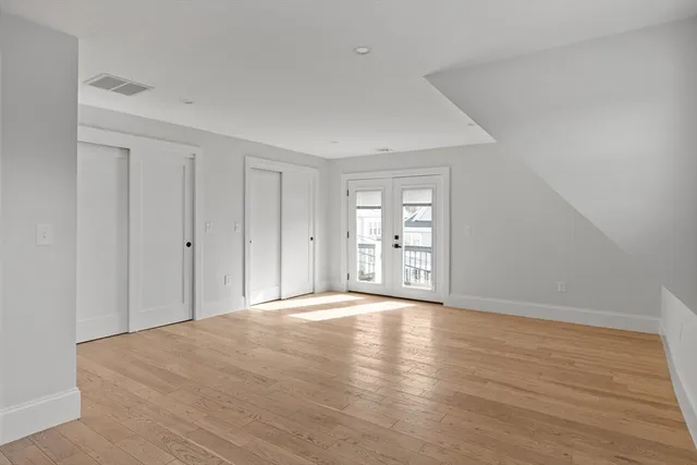 a view of an empty room with wooden floor and windows