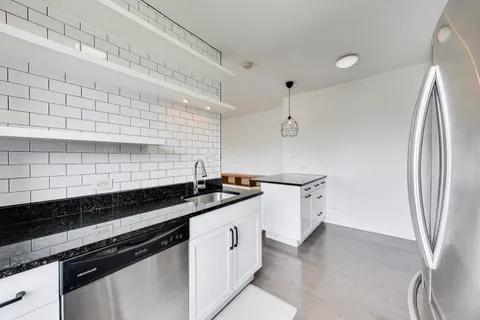 a kitchen with granite countertop white cabinets and stainless steel appliances