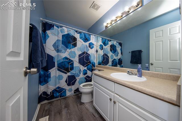 7511 Coffee Road Peyton, CO 80831 - Photo 33 of 38 Bathroom with vanity, toilet, wood finished floors, and a shower with shower curtain