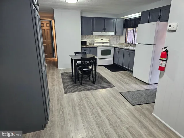 a kitchen with stainless steel appliances a refrigerator a stove a sink and white cabinets with wooden floor