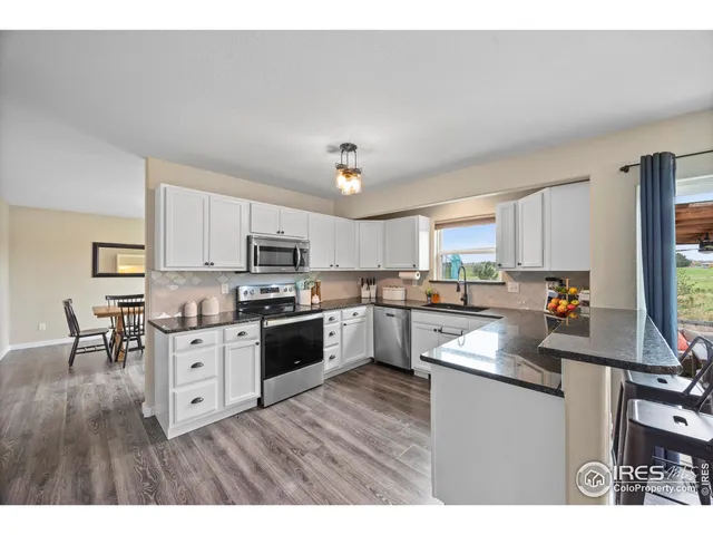 a kitchen with cabinets wooden floor and stainless steel appliances