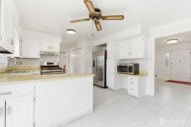 a kitchen with stainless steel appliances granite countertop a refrigerator a stove a sink a stove with white cabinets