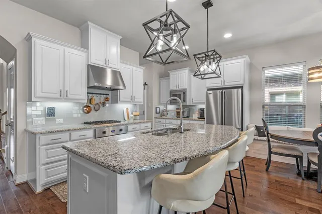 a kitchen with stainless steel appliances granite countertop a kitchen island a stove a table and chairs in it