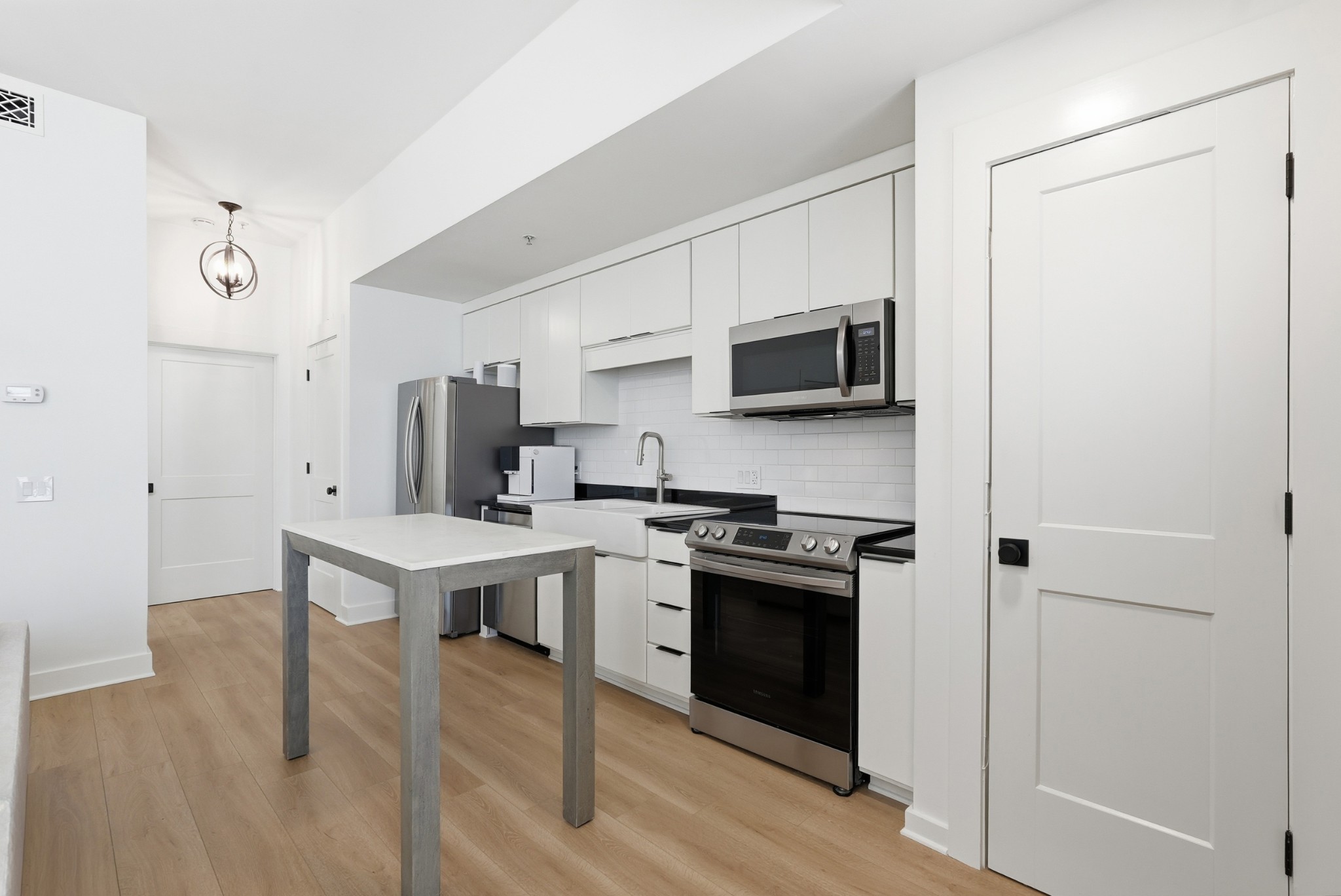 520 Madison Street Nashville, TN 37208 - Photo 6 of 16 a kitchen with stainless steel appliances a stove top oven a sink a refrigerator white cabinets and wooden floor