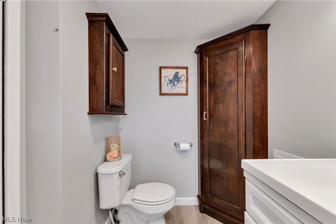 8704 Columbia Road Olmsted Falls, OH 44138 - Photo 25 of 34 half bath featuring a white toilet, recessed wall cabinet with wood-finish doors, corner wood-finish storage cabinet, and light gray walls