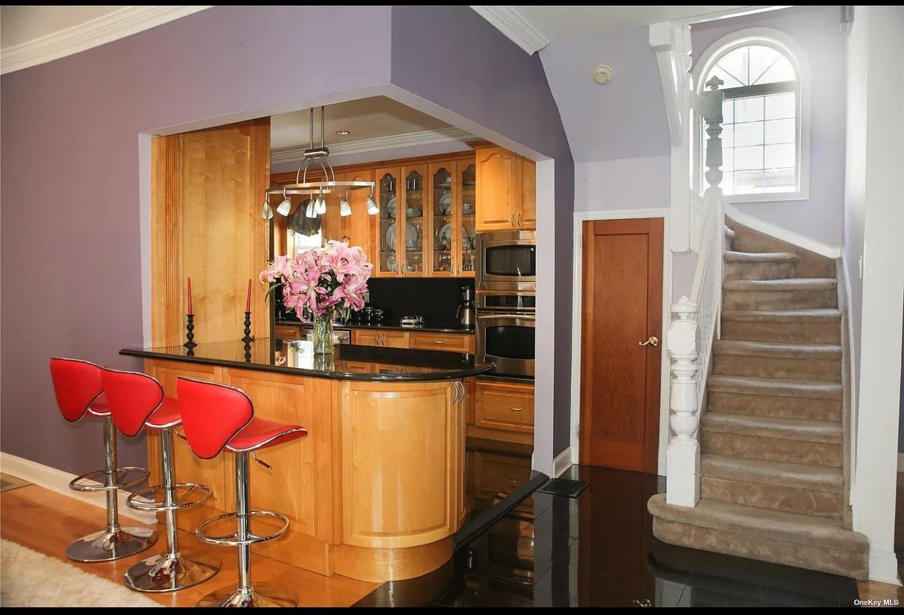 94-18 Lefferts Boulevard Queens, NY 11419 - Photo 7 of 8 Bar with stainless steel appliances, stairs, baseboards, crown molding, and hanging light fixtures