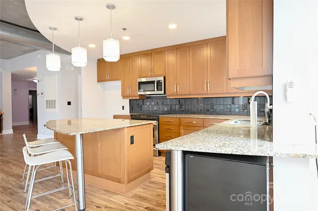 a kitchen with kitchen island granite countertop a sink counter top space appliances and cabinets